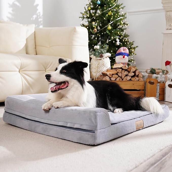 Dog lying on a gray pet bed in a cozy living room with a Christmas tree in the background.